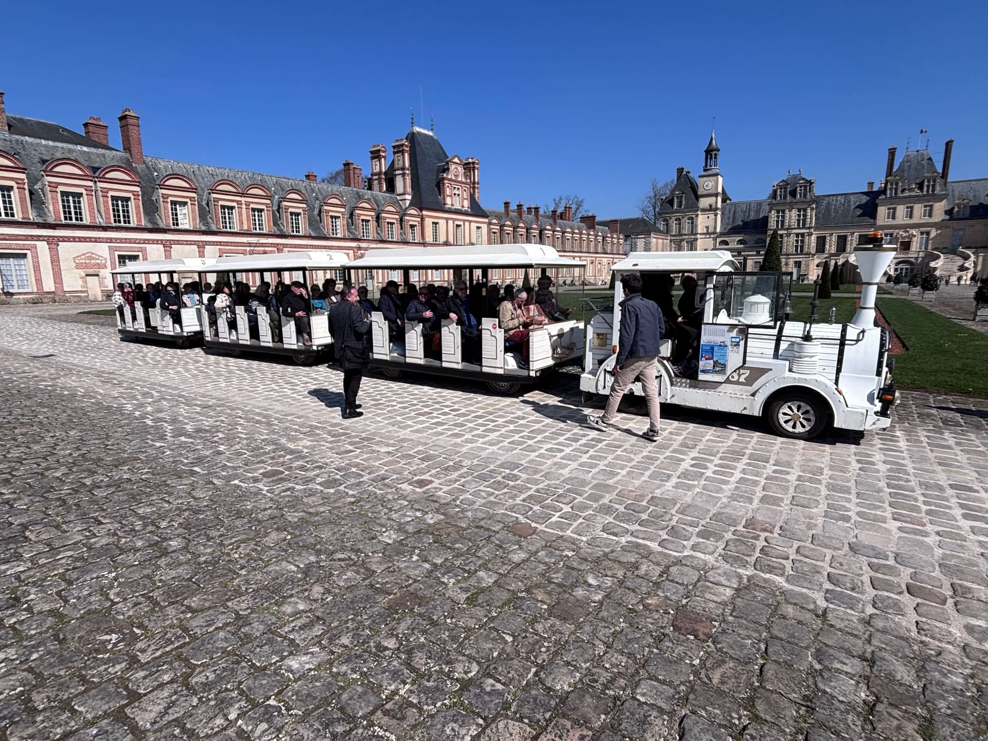Le petit train touristique devant la façade du Château de Fontainebleau